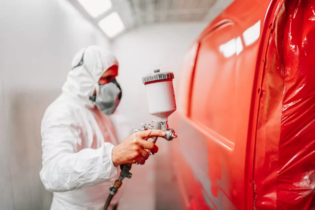 Auto paint technician painting a red car