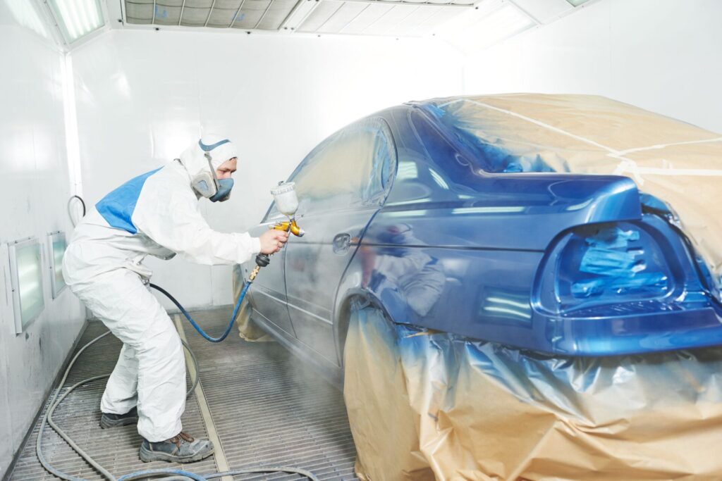 Paint technician repainting a blue car