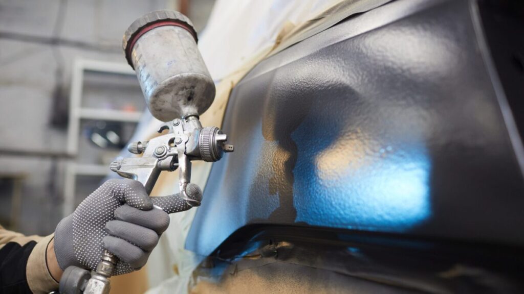 Auto technician repainting a car