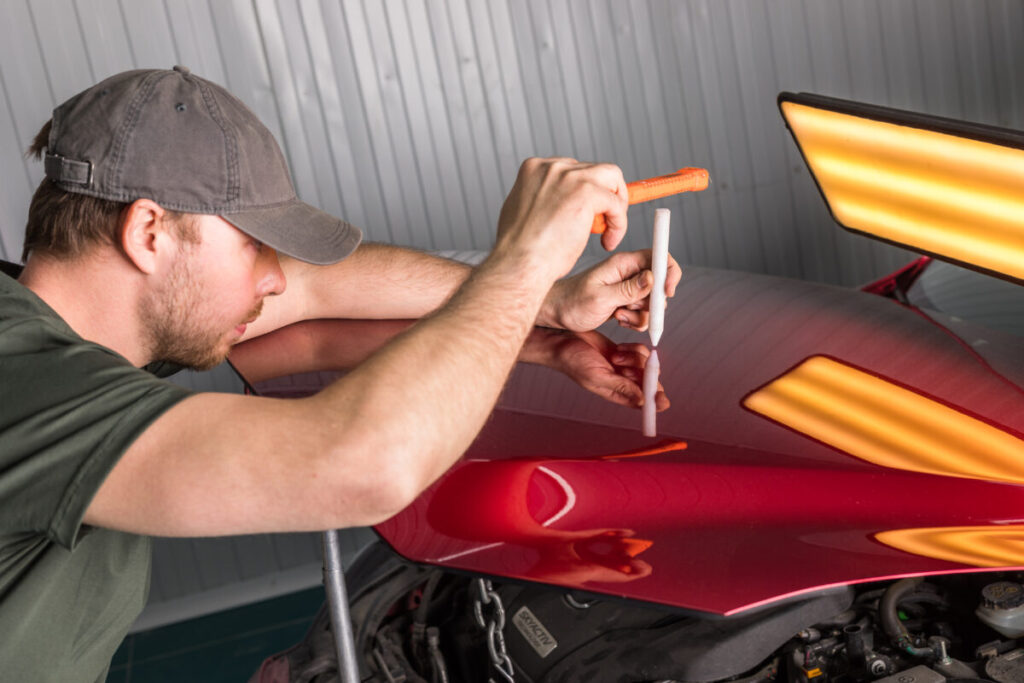 Technician repairing car dents using PDR technology